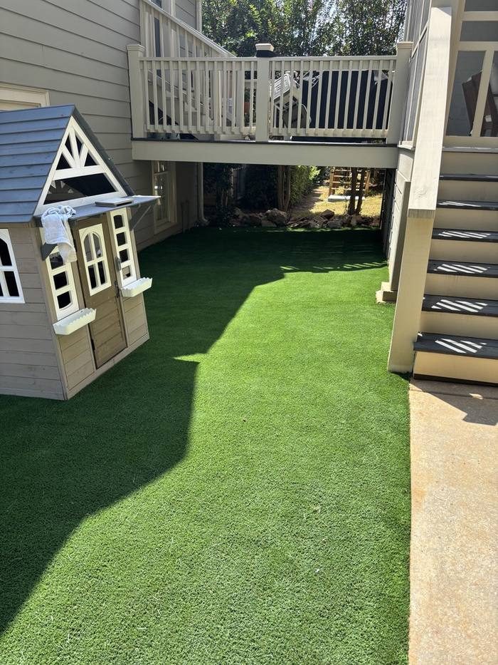 Artificial turf installation beside a playhouse and deck